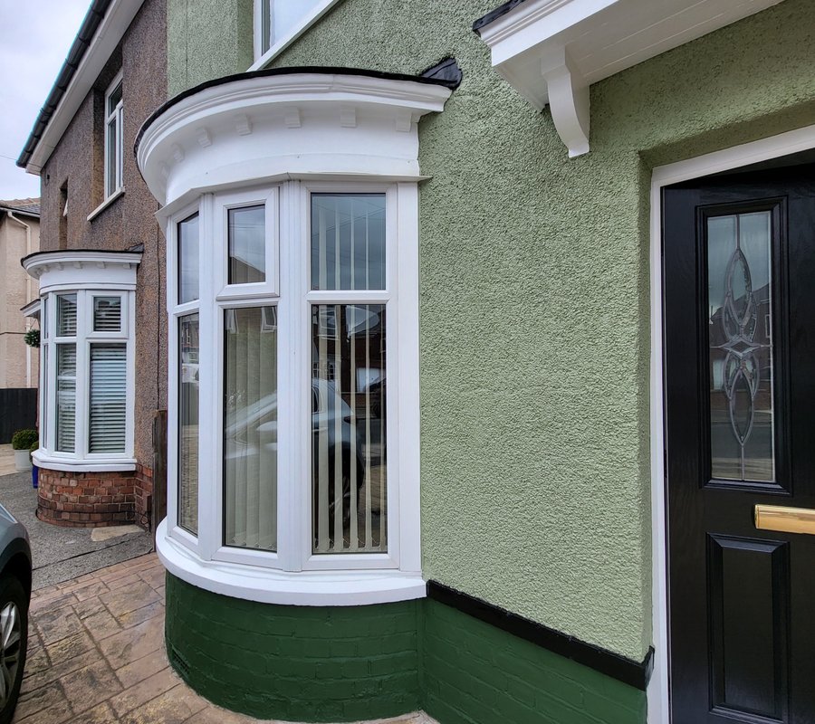 Green rendered house with white exterior trim