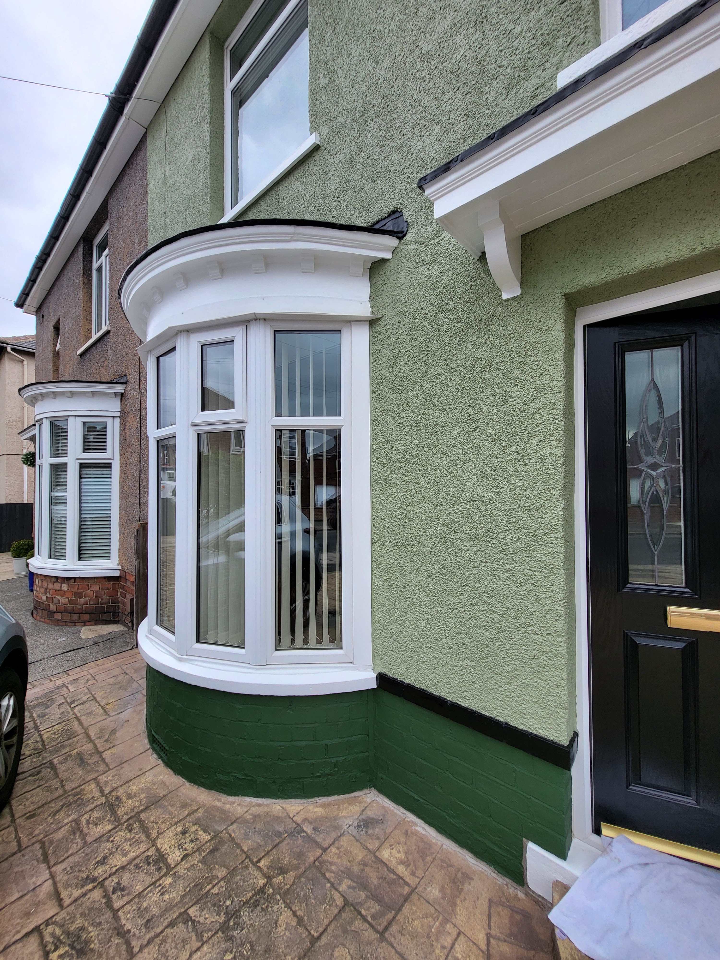green rendered house with white exterior trim