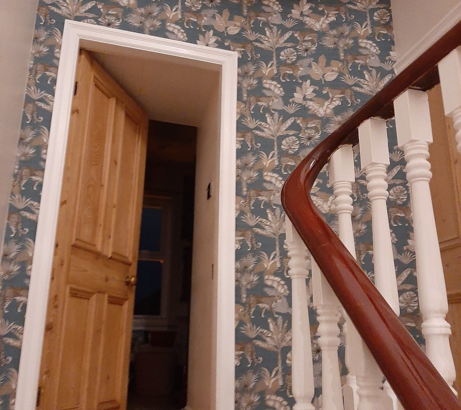 Patterned wallpaper fitted around a staircase and doorway