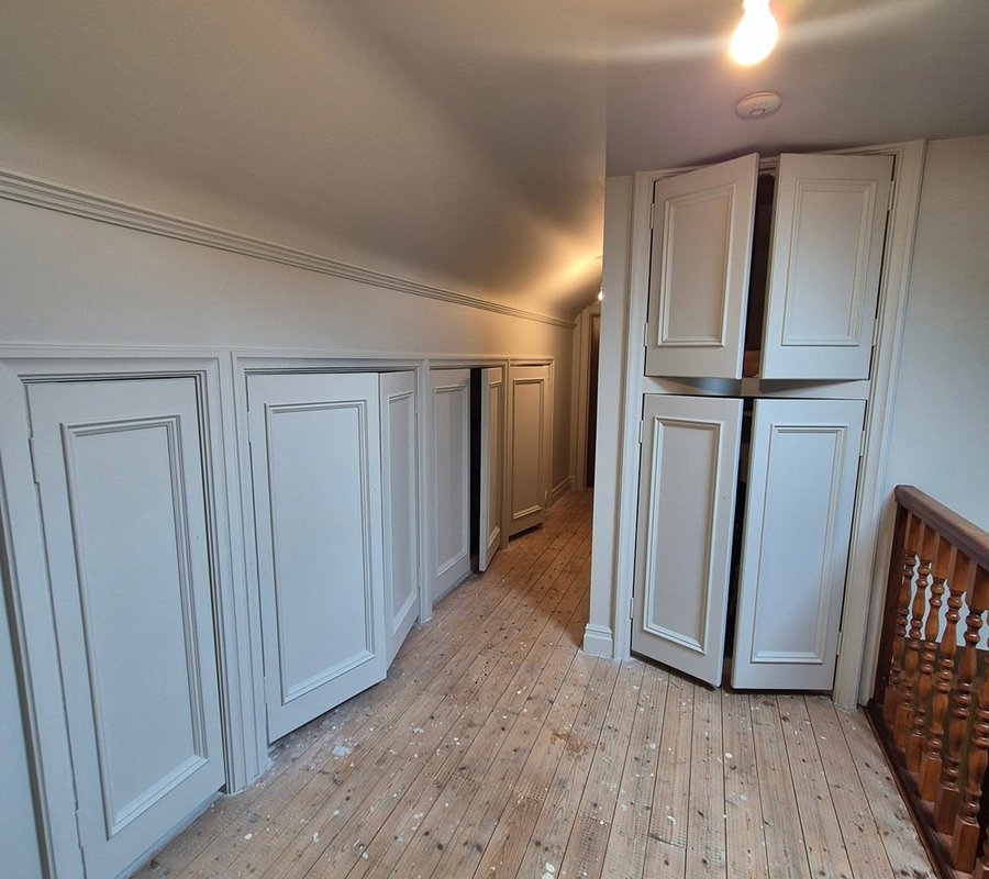Painted fitted cupboards and wall panelling