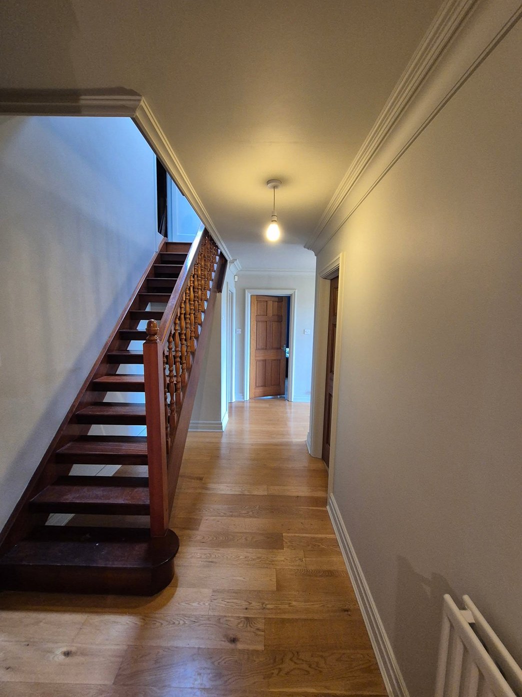 Freshly decorated hallway with neutral walls, detailed coving and restored wooden staircase