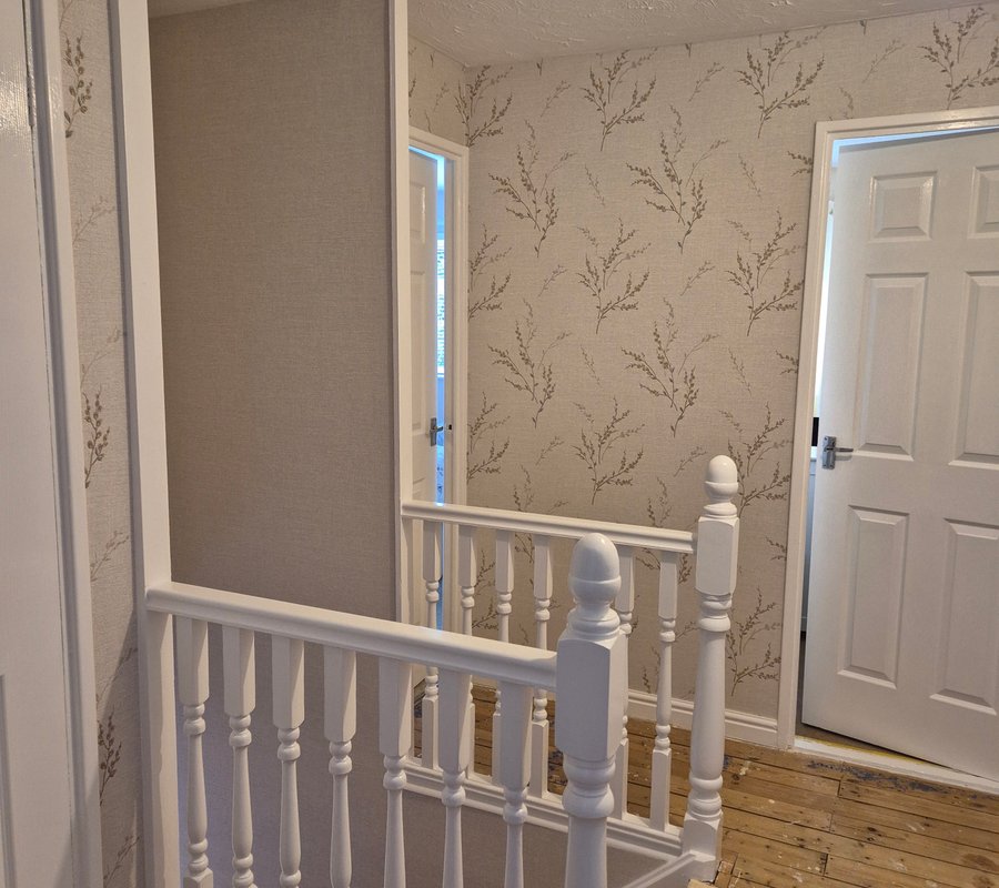 Wallpapered landing with freshly painted white woodwork